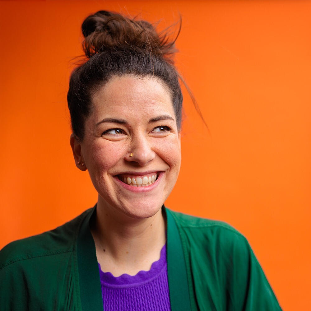 Caro Turlings portrait image, smiling with orange background